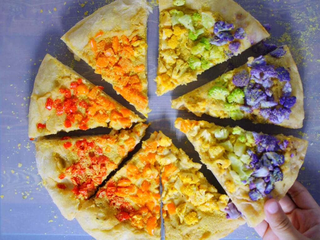 Rainbow Vegan Hummus Pizza grabbing a slice