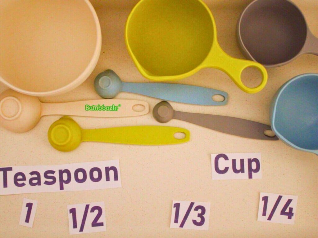 Measuring cups and spoons labeled with paper cutouts for a hands-on kitchen learning activity