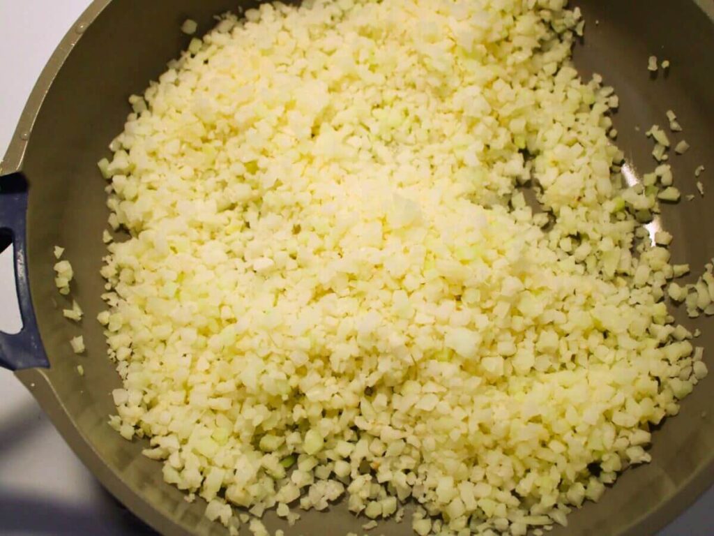 Riced cauliflower cooking in a pan for vegan ricotta