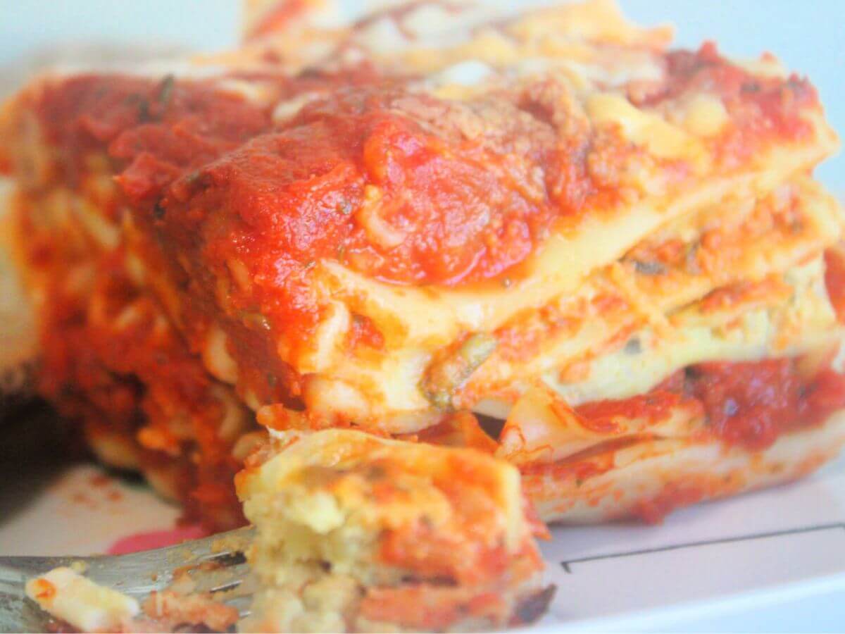 Slice of kid-friendly vegan vegetable lasagna showing layered noodles, vegetables, and dairy-free cheese