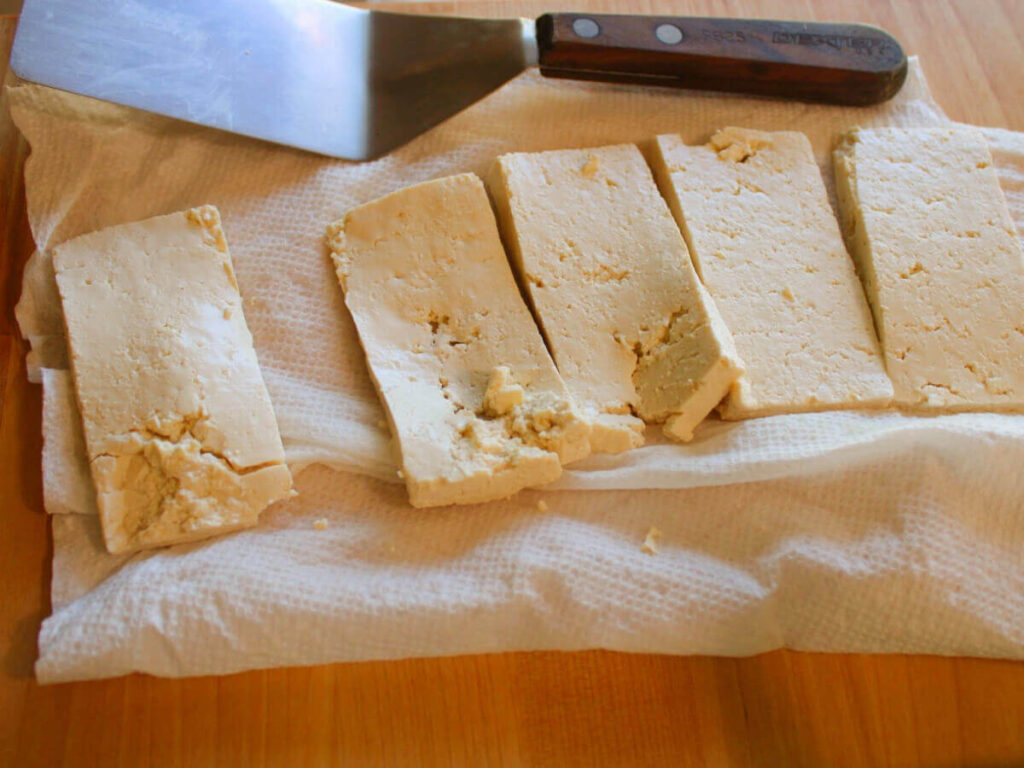 Tofu cut into rectangles on a paper towel ready to make vegan turkey cutlets.