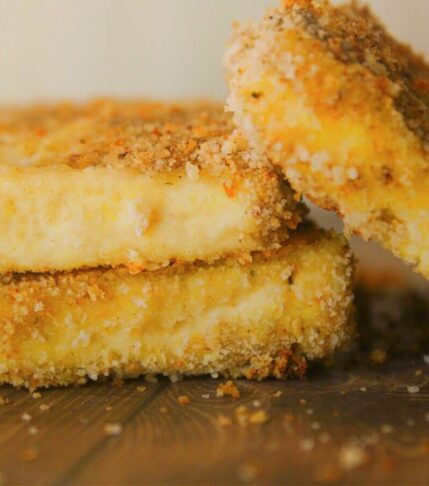 Breaded vegan turkey cutlets made from tofu stacked with crumbs around them.