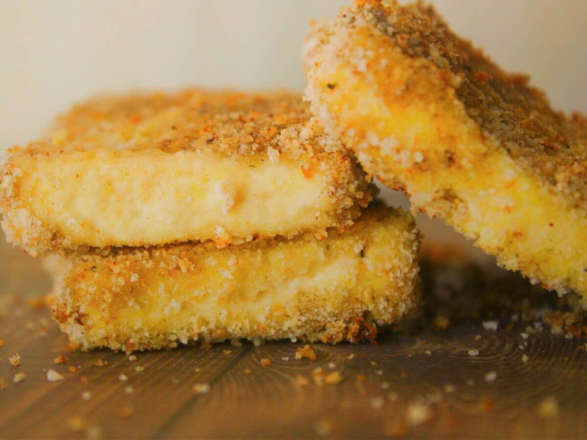 Breaded vegan turkey cutlets made from tofu stacked with crumbs around them.