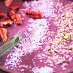 Close-up of açaí berry smoothie bowl with coconut shreds, hemp seeds, and pecans