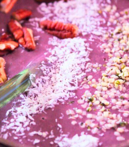 Close-up of açaí berry smoothie bowl with coconut shreds, hemp seeds, and pecans