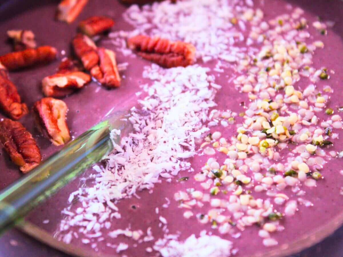 Close-up of açaí berry smoothie bowl with coconut shreds, hemp seeds, and pecans