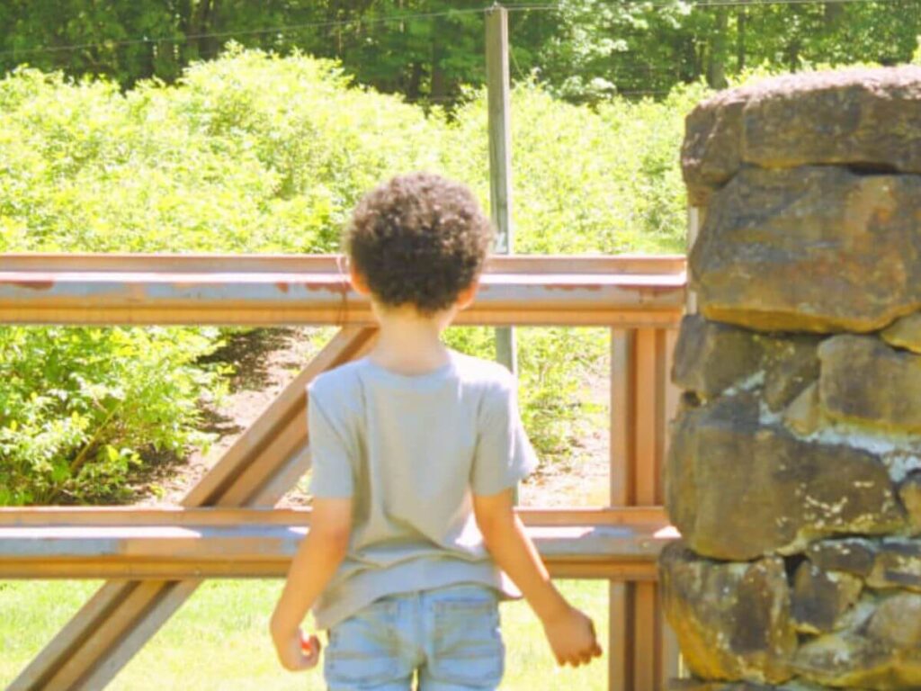 Child standing outside on a hot summer day with back facing the camera