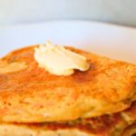 Close-up of golden vegan chia seed pancakes with butter and maple syrup