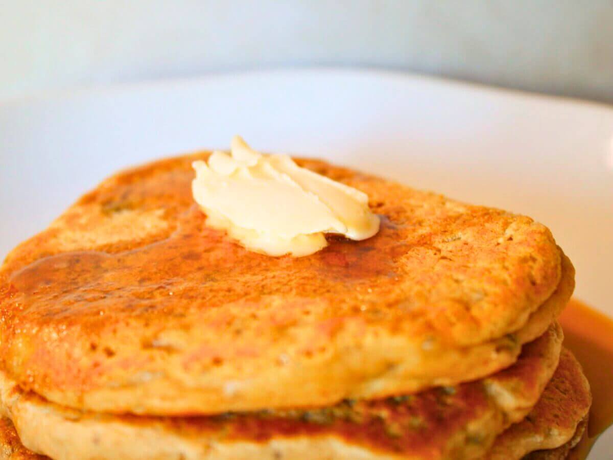 Close-up of golden vegan chia seed pancakes with butter and maple syrup