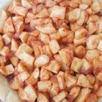 apples piled high in pie crust for overflowing vegan apple pie