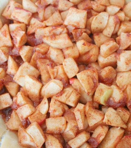 apples piled high in pie crust for overflowing vegan apple pie