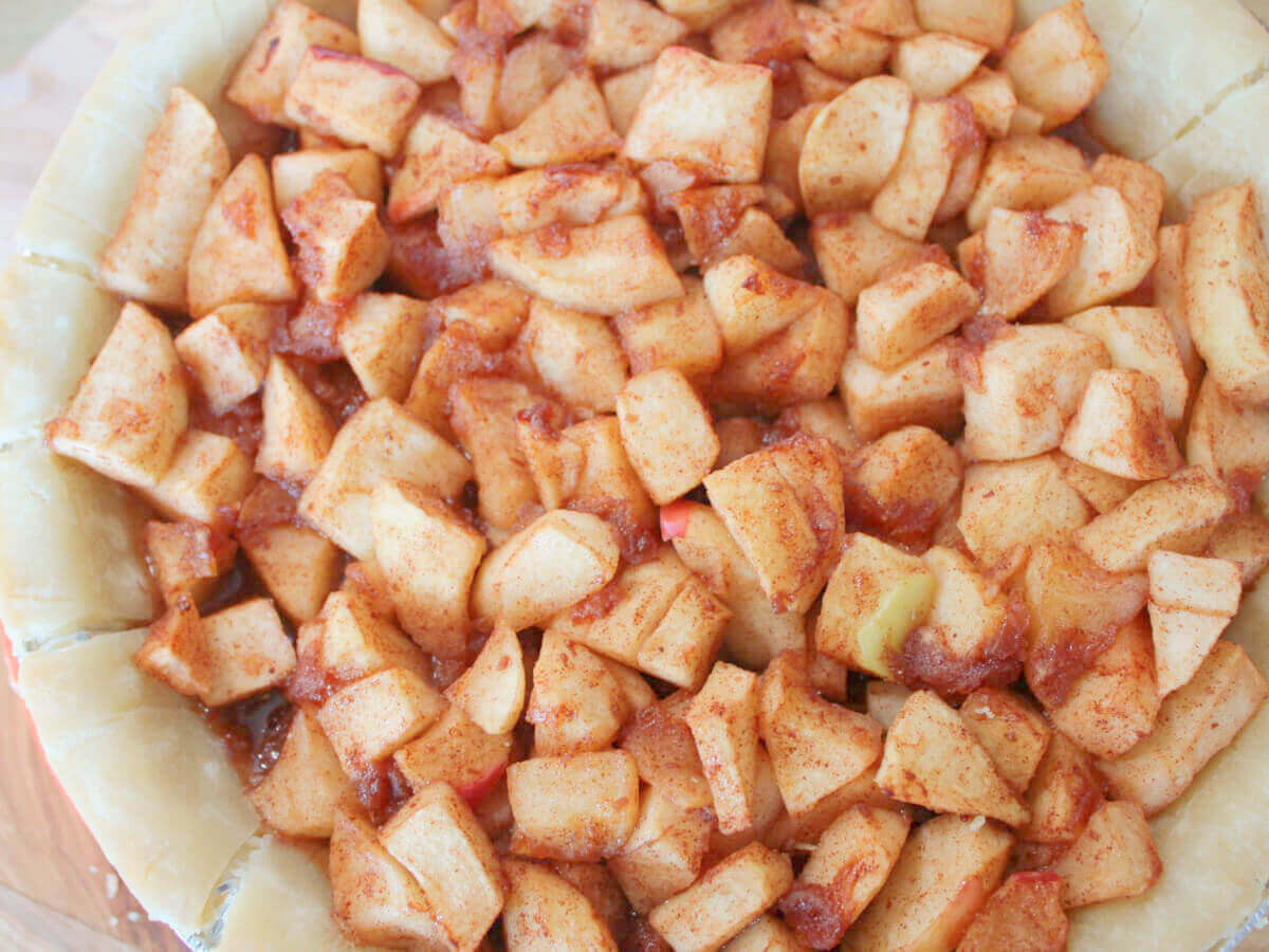 apples piled high in pie crust for overflowing vegan apple pie