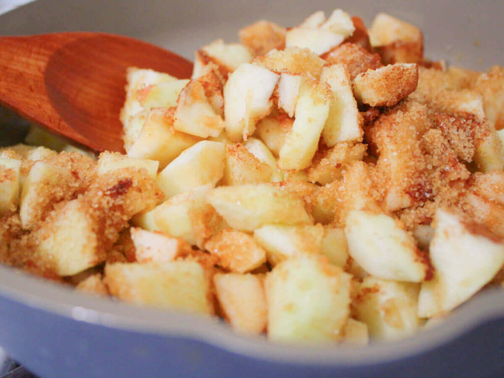 apples cooking in pan with cinnamon and sugar for vegan apple pie filling