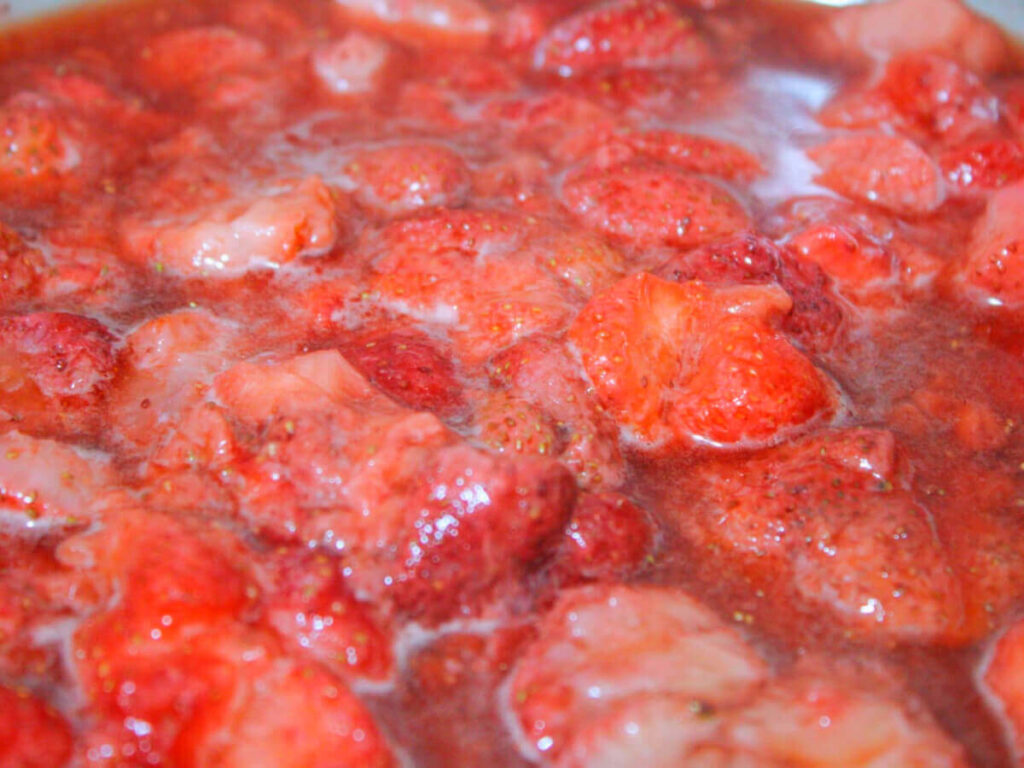 frozen strawberries defrosting in pan for homemade strawberry jam