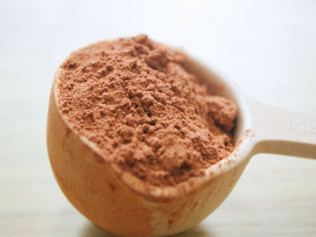 Cacao powder spilling from a tablespoon during vegan chocolate treat preparation