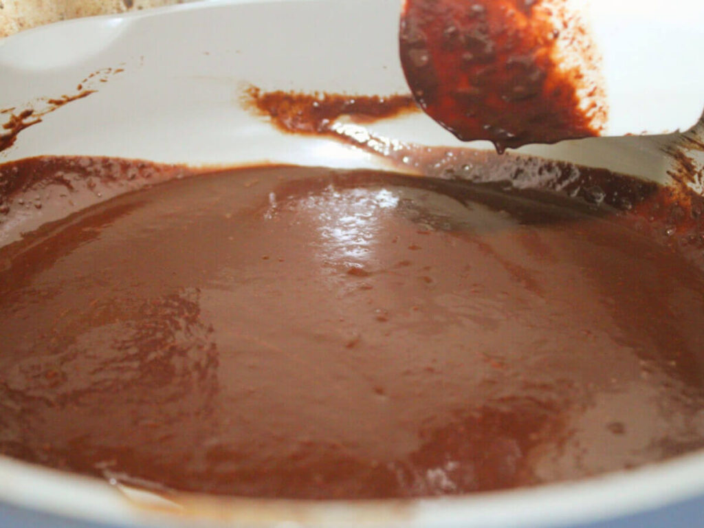 Melted chocolate dripping from a spatula in a saucepan