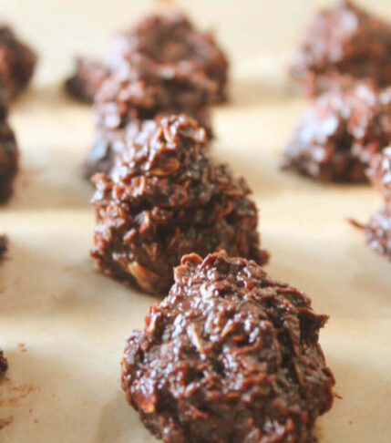 No-Bake Vegan Chocolate Goodies rolled into round balls on a lined cookie sheet