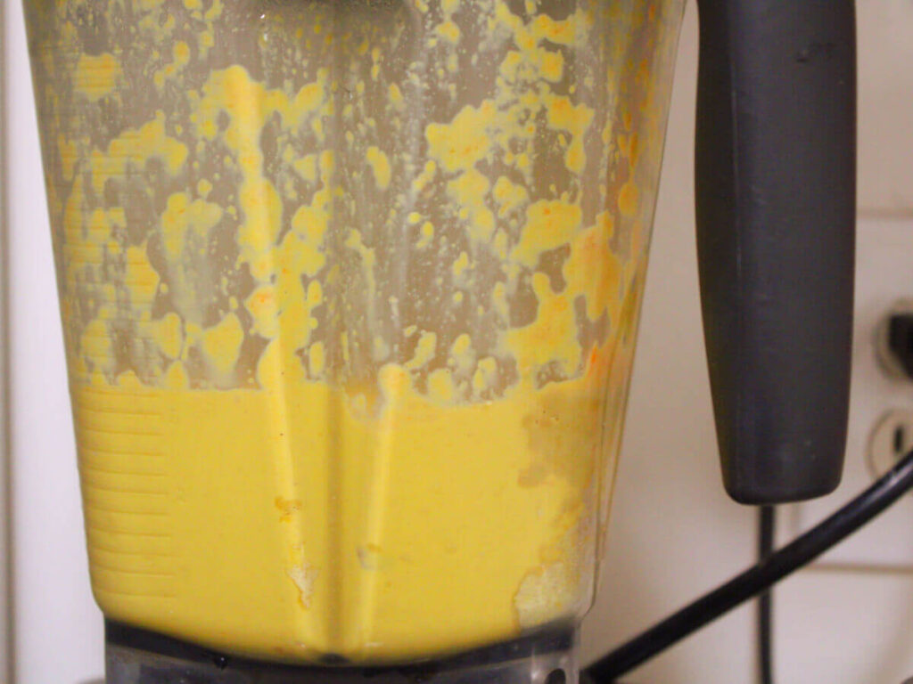 Dairy-free cheese sauce blending in a Vitamix for kid-friendly vegan broccoli cheddar rice.