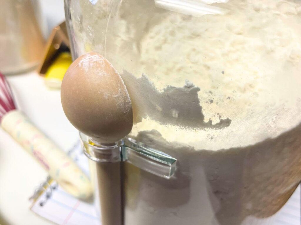 Glass jar filled with flour and wooden spoon for baking
