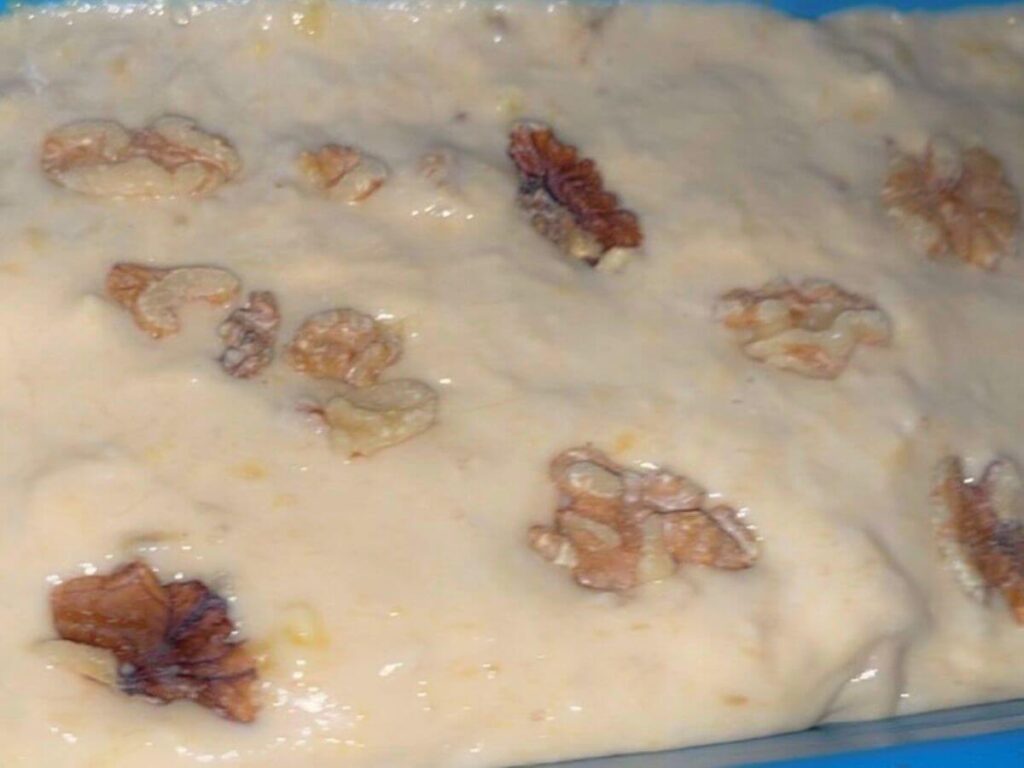 Walnuts pressed into vegan banana bread batter in loaf pan