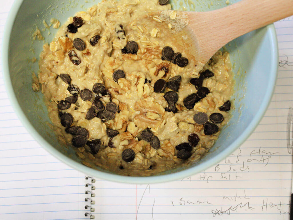Mixing bowl with banana bread cookie batter sitting on a handwritten recipe notebook