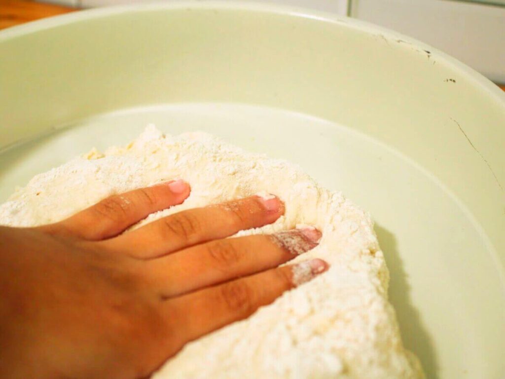 Child touching sticky healthy vegan pizza dough with hands during a hands-on kid-friendly cooking activity