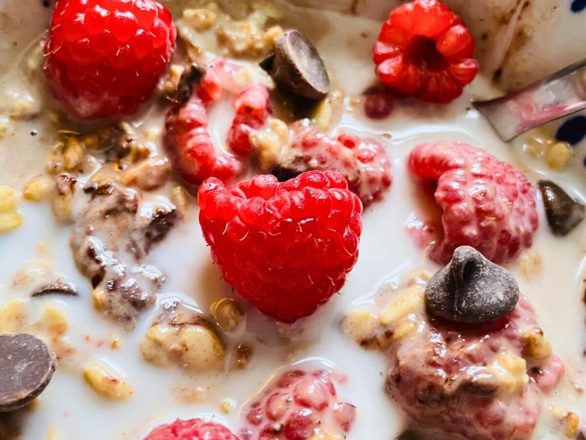 Finished vanilla overnight oats topped with fresh raspberries and chocolate chips for a simple, kid-friendly make-ahead breakfast option