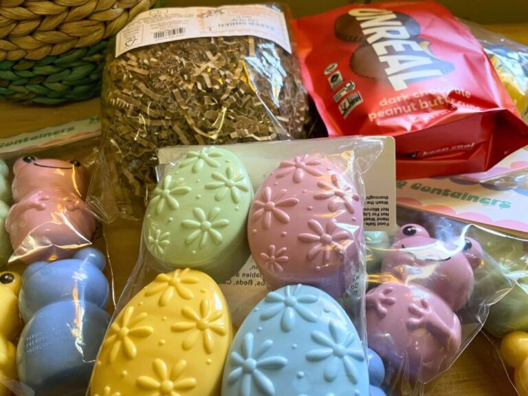 Vegan Easter basket ideas for older kids including books, Unreal peanut butter cups, toy frog, and egg game containers on a table