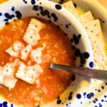 vegan tomato rice soup with rice and saltine crackers in bowl