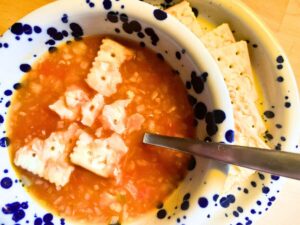 vegan tomato rice soup with rice and saltine crackers in bowl
