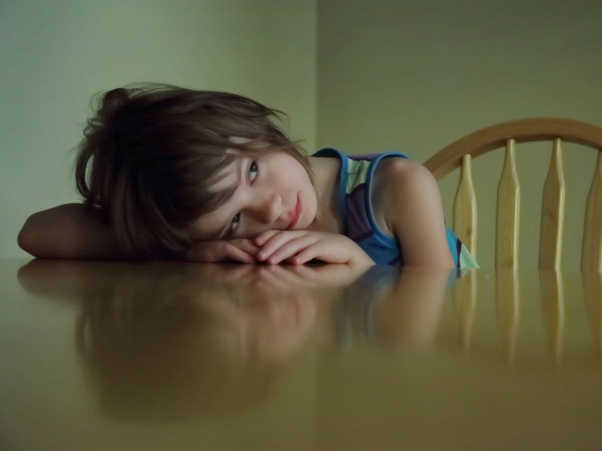 Child sitting alone at a dinner table with head resting, reflecting feelings of disconnection during mealtime