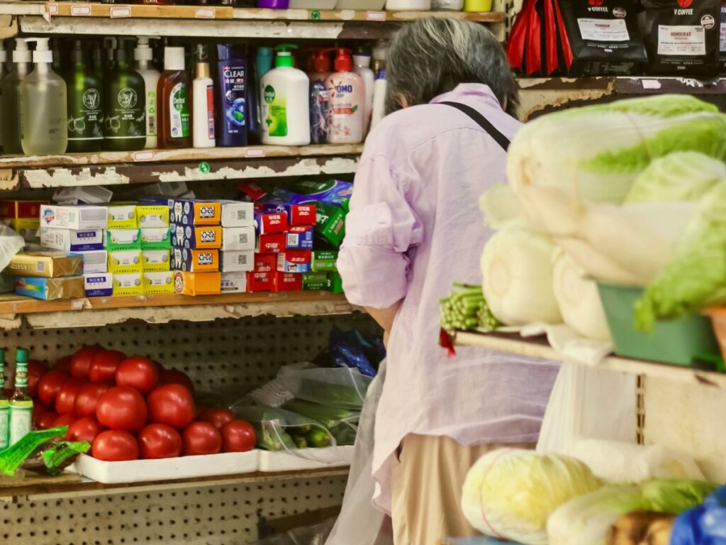 Elderly woman examining grocery prices in a store as food costs continue to rise