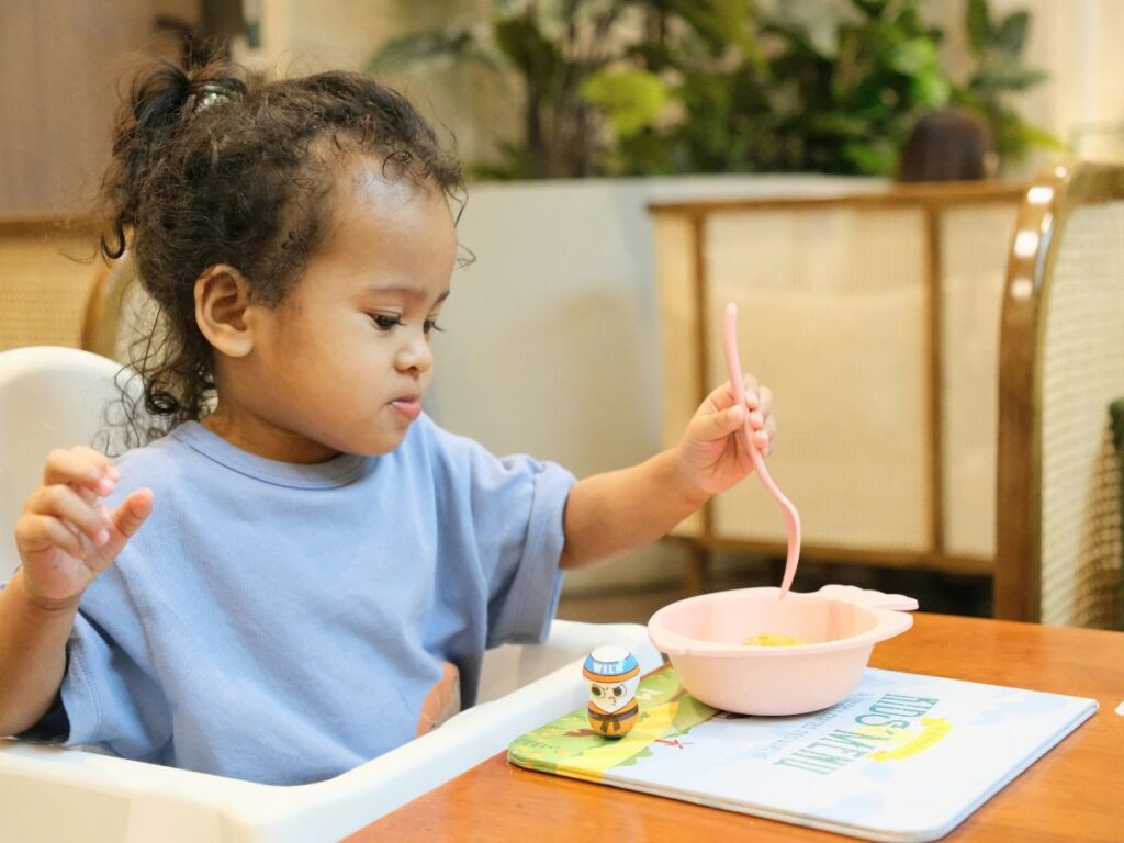 young child sitting at table unsure about eating meal