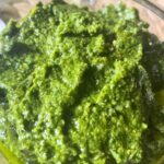 Vegan basil pesto in a round glass container, smooth and bright green