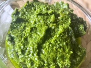 Vegan basil pesto in a round glass container, smooth and bright green